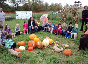 Pre-school students enjoying circle time in a pumpkin patch on a field trip in PA to Hellerick's Family Farm