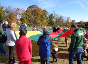 Elementary school students and field trip chaperons playing the parachute game at Hellerick's family farm.