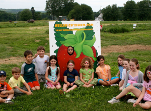 Elementary school children on a field trip in PA posing in front of a tomato cut out in a field.