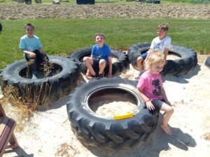 Kids playing in old tires as one of the fun outdoor activities at Hellerick's Family Farm