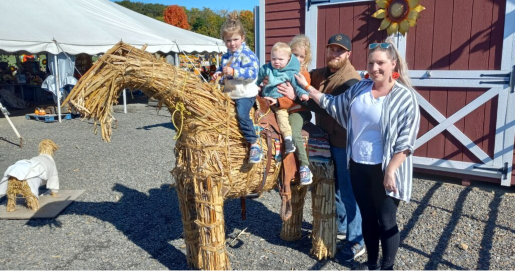 A family posing with a horse made of hay